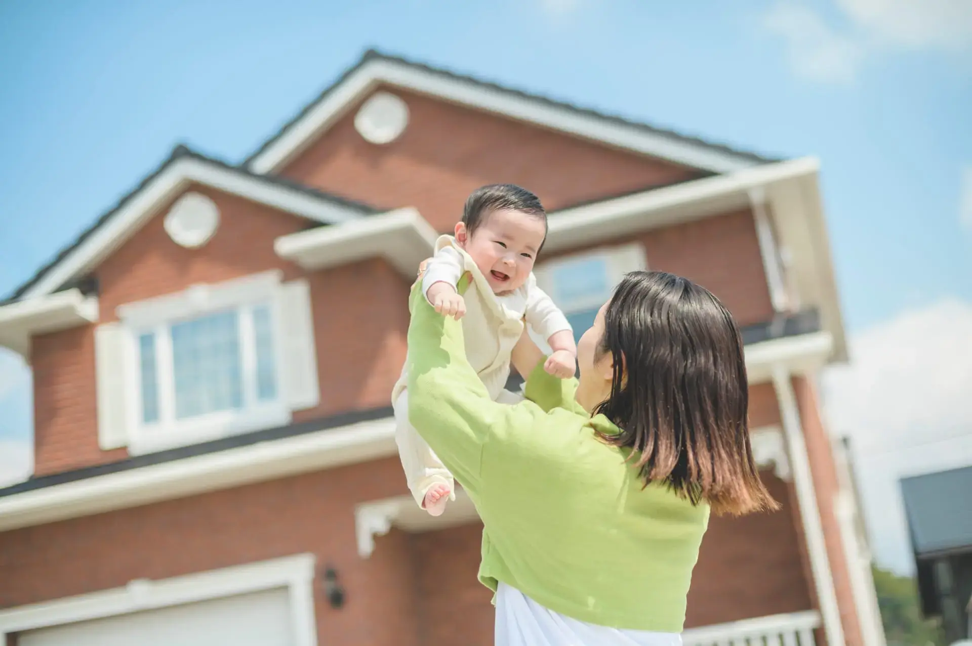セルコホームの外観と赤ちゃんを抱く母親